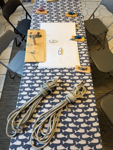 Ein Tisch mit einem maritimen Muster, darauf liegen Seile und einige Stühle.